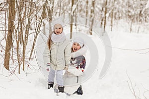 Two girlfriends playing in a winter forest.