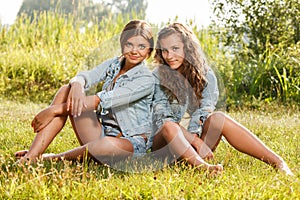 Two girlfriends sitting on grass