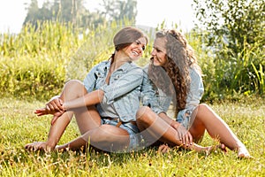 Two girlfriends sitting on grass