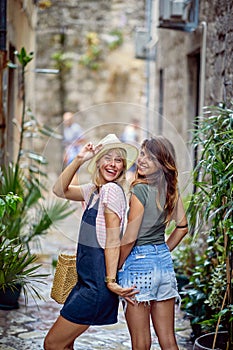 Two girlfriends on strret making funny face expressions, having fun together. Young women walking on street of European city. photo