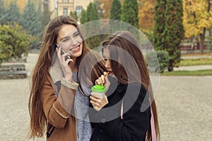 Two girlfriends try to warm up with a hot drink in the outdoors