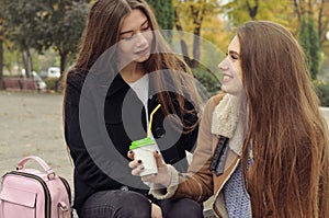 Two girlfriends try to warm up with a hot drink in the outdoors