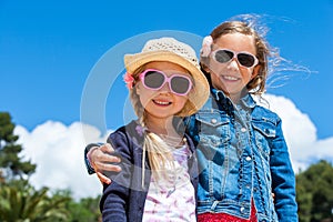 Two girlfriends wearing sunglasses outdoors.