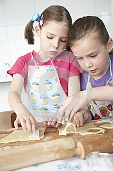 Two girls (5-6) cutting dough in kitchen