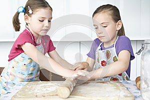 Two girls (5-6) cutting dough in kitchen