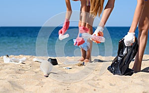 Two girls activists collect garbage from the beach in the foe of the sea.