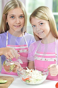 Two girls in aprons preparing fresh salad