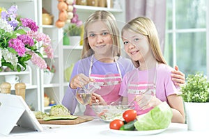 Two girls in aprons preparing fresh salad