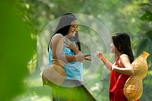 Two girls Asian women with traditional clothing stand in the rainforest.