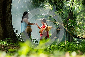 Two girls Asian women with traditional clothing stand in the rainforest.