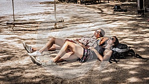 Two girls backpackers lying on ranches on tropical beach sand in shade photo