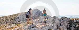 two girls with backpacks walk along a mountain path