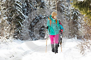 two girls with backpacks walk along a path in the winter mountains. hiking in the mountains