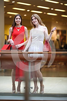 Two girls with bags stands near railing of balcony photo
