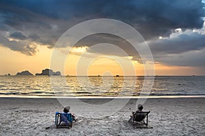 Two girls in beach chairs admiring the sunset at sea