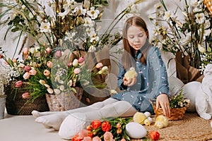 Two girls in a beautiful Easter photo zone with flowers, eggs, chickens and Easter bunnies. Happy Easter holiday.