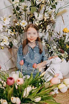 Two girls in a beautiful Easter photo zone with flowers, eggs, chickens and Easter bunnies. Happy Easter holiday.