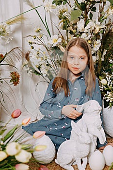 Two girls in a beautiful Easter photo zone with flowers, eggs, chickens and Easter bunnies. Happy Easter holiday.