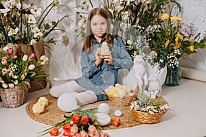 Two girls in a beautiful Easter photo zone with flowers, eggs, chickens and Easter bunnies. Happy Easter holiday.