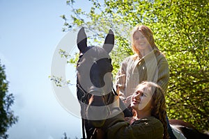 Two girls with big horse in a summer day