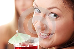 Two girls in bikini drink fruit cocktails