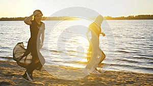 Two girls in a black dress walk along the beach and dance