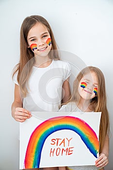 Two girls drew rainbow and poster stay home. photo