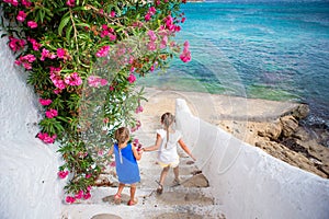 Two girls in blue dresses having fun outdoors. Kids at street of typical greek traditional village with white walls and