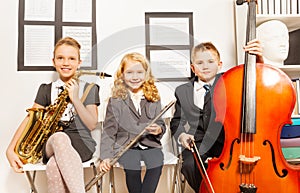 Two girls and boy playing musical instruments