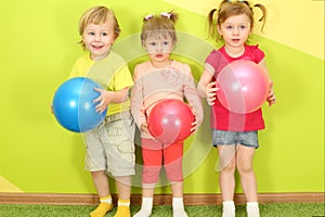 Two girls and a boy standing with balls in