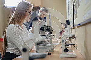 Two girls and a boy work with microscopes