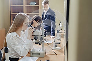 Two girls and a boy work with microscopes