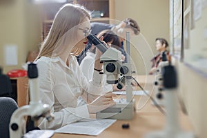 Two girls and a boy work with microscopes