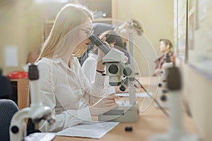 Two girls and a boy work with microscopes