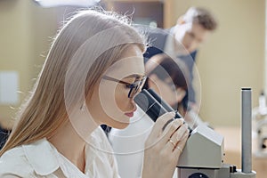 Two girls and a boy work with microscopes