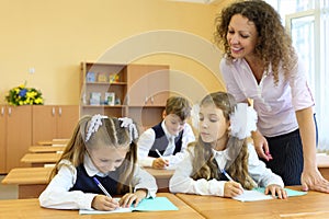 Two girls and boy write at school desks in photo
