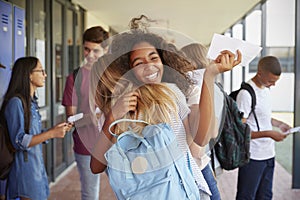 Two girls celebrating exam results in school corridor