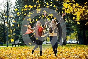 Two girls cheerfully spend time in the autumn park.