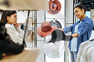 Two girls choosing hats in clothing store