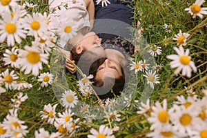 Two girls with closed eyes in dark blue and white dresses in sunny day lying down  and sleeping in chamomile field