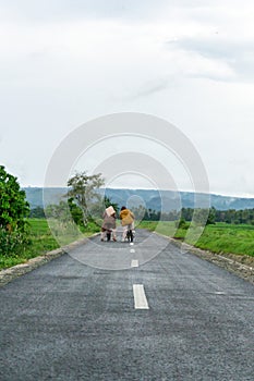 Two girls cycling with mountain and paddy rice field view