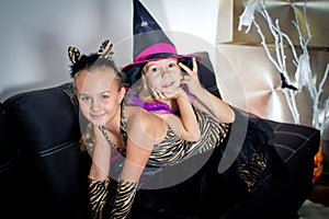 Two girls disguised as a tiger and as a witch are waiting for some candies in All Saints' Day.