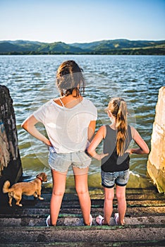 Two girls with dog standing on dock