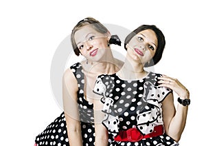 Two girls dressed in the style of pin-up posing on a white background