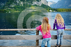Two girls enjoying the scenic view of Hallstatt lakeside town in the Austrian Alps in beautiful evening light on beautiful day in