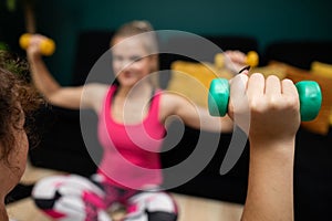 Two girls exercise with dumbbells. Close-up view. Fitness in the living room.