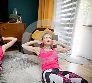 Two girls exercise their abdominal muscles together. Gymnastics at home during pandemonium. Fitness in the living room.