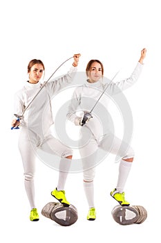 Two girls are fencers, in uniform for fencing and holding swords. Isolated.