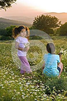 Two girls flowers field at sunset