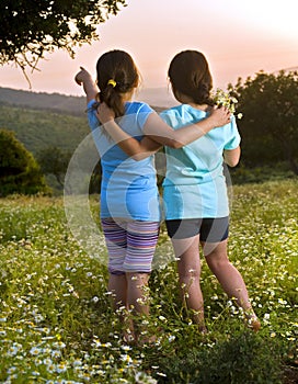 Two girls flowers field at sunset